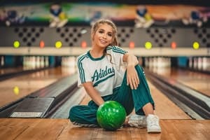 Woman sitting on bowling alley floor with bowling ball
