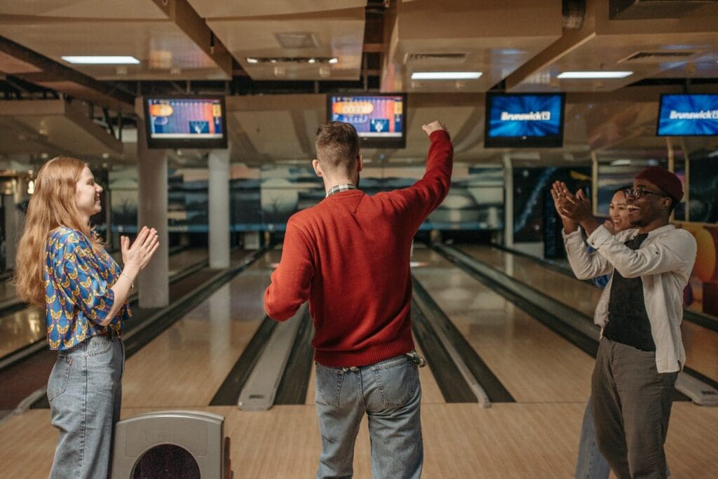 Group of friends cheering for man at bowling alley
